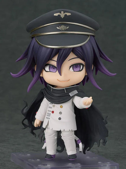 Nendoroid Kokichi Oma with purple hair, violet eyes, a black peaked cap and cape, and a white outfit, smiling with both arms extended.