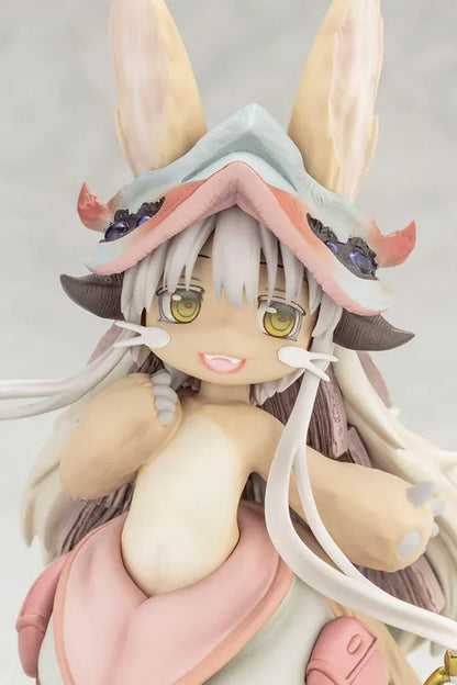 Made in Abyss The Awakening Mystery Nanachi Figure (Rerelease) featuring a fluffy rabbit-like character with long cream-colored ears, golden eyes, an oversized explorer hat, pink and beige clothing, and long flowing hair standing on a detailed scenic base with green moss, rocks, and blue water.