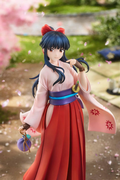 Sakura Wars Sakura Shinguji 1/7 Scale Figure featuring a dark blue-haired anime girl with brown eyes, a red hair ribbon, pink kimono-style top, purple obi, flowing red hakama skirt, sword accessory, and purple pouch on a transparent circular base.