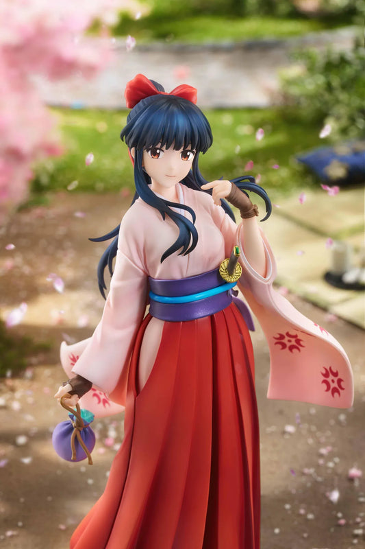 Sakura Wars Sakura Shinguji 1/7 Scale Figure featuring a dark blue-haired anime girl with brown eyes, a red hair ribbon, pink kimono-style top, purple obi, flowing red hakama skirt, sword accessory, and purple pouch on a transparent circular base.