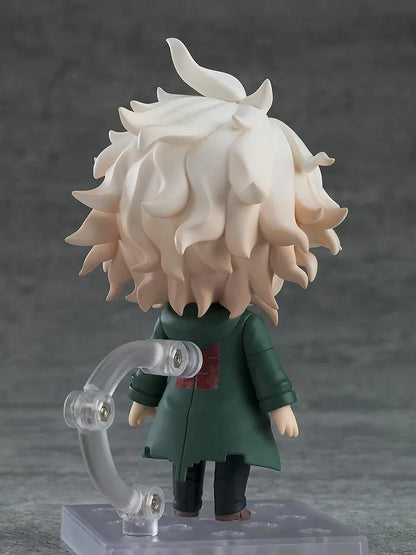 Nendoroid Nagito Komaeda with tousled white hair, pale green eyes, a green coat, white printed shirt, and black trousers, extending one hand.