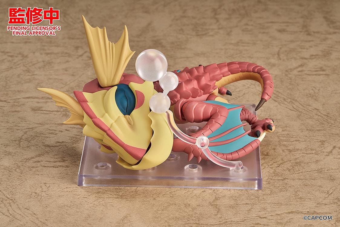 Monster Hunter Nendoroid Yian Kut-Ku with yellow ear fans, an open beak, pink-red scales, and spread wings with turquoise membranes.