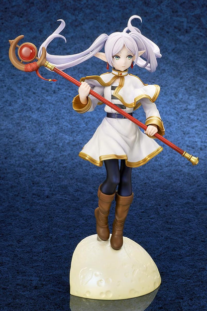 Frieren vs Aura 1/7 scale figure holding a red staff while wearing her white-and-gold mage outfit on a rounded display base.