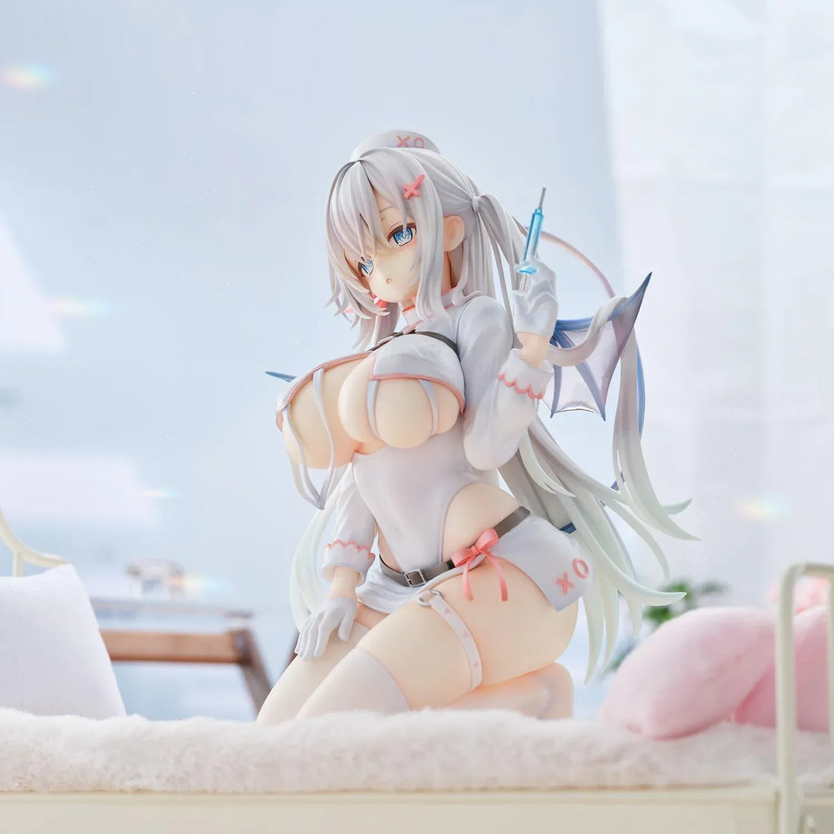 Succubus Nurse Makina figure kneeling in a white and pink nurse outfit with silver hair, batlike wings, a demon tail, and a translucent syringe.
