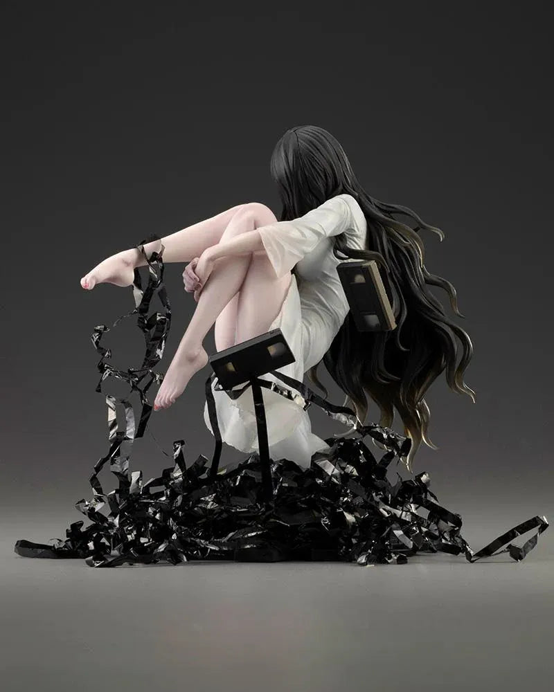 Sadako BISHOUJO Sadako 1/7 Scale Figure (Rerelease) featuring a long black-haired horror character wearing a flowing white dress, seated above a pile of VHS tapes with tangled black film ribbons.