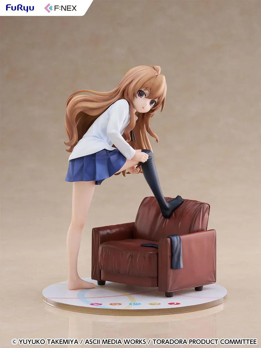 1/7 scale Toradora figure of Taiga Aisaka at home, barefoot and leaning on a leather armchair while pulling on a black thigh-high sock, wearing her school shirt and blue skirt.