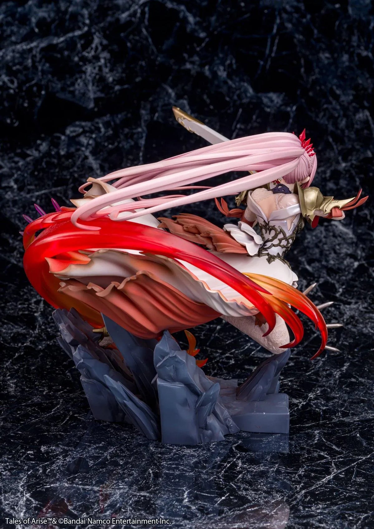 Tales of Arise Shionne 1/7 Scale Figure featuring a pink-haired anime character with blue eyes, an ornate white battle dress, gold armor, and lace stockings, aiming a detailed rifle while suspended in a dynamic pose surrounded by translucent red and orange effects on a rocky display base.