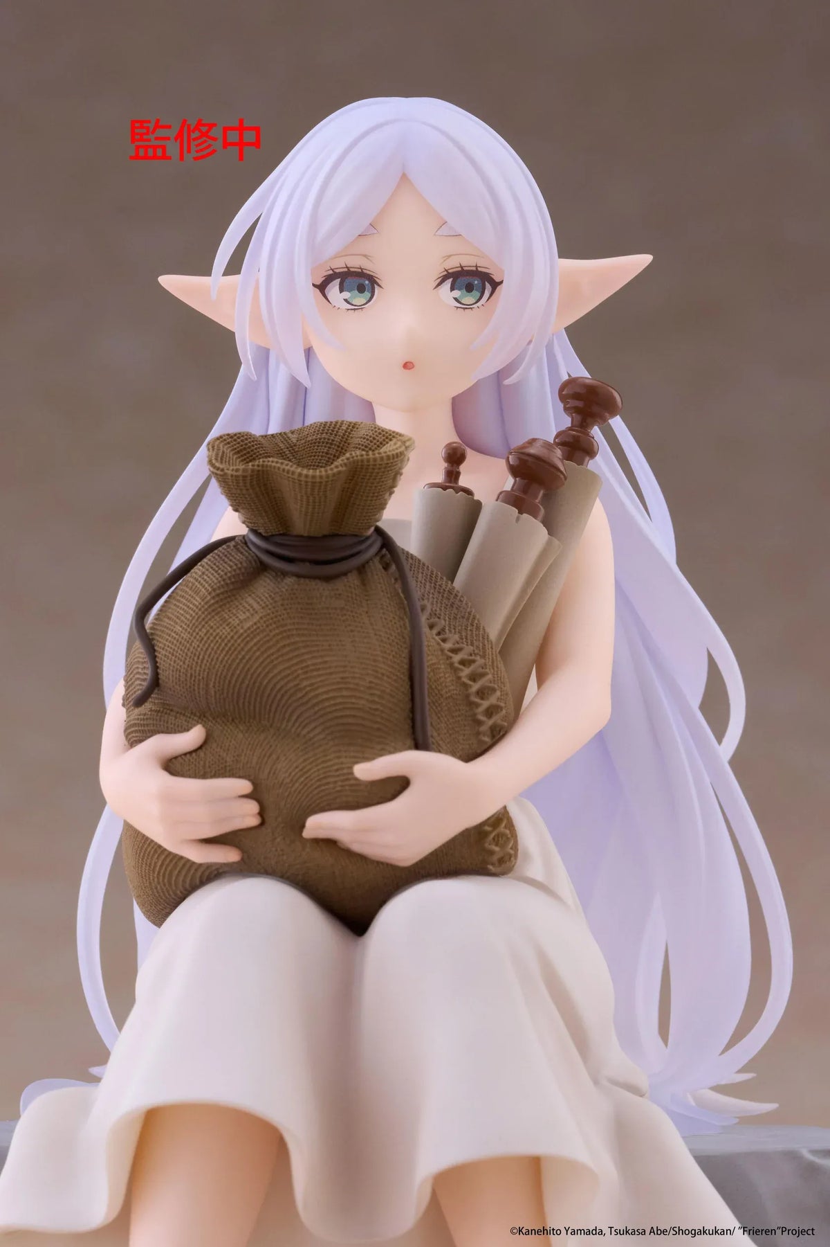 Desktop Cute Frieren In Training Ver. figure seated on a gray stone block, wearing a cream dress and brown sandals while holding a sack beside rolled scrolls.