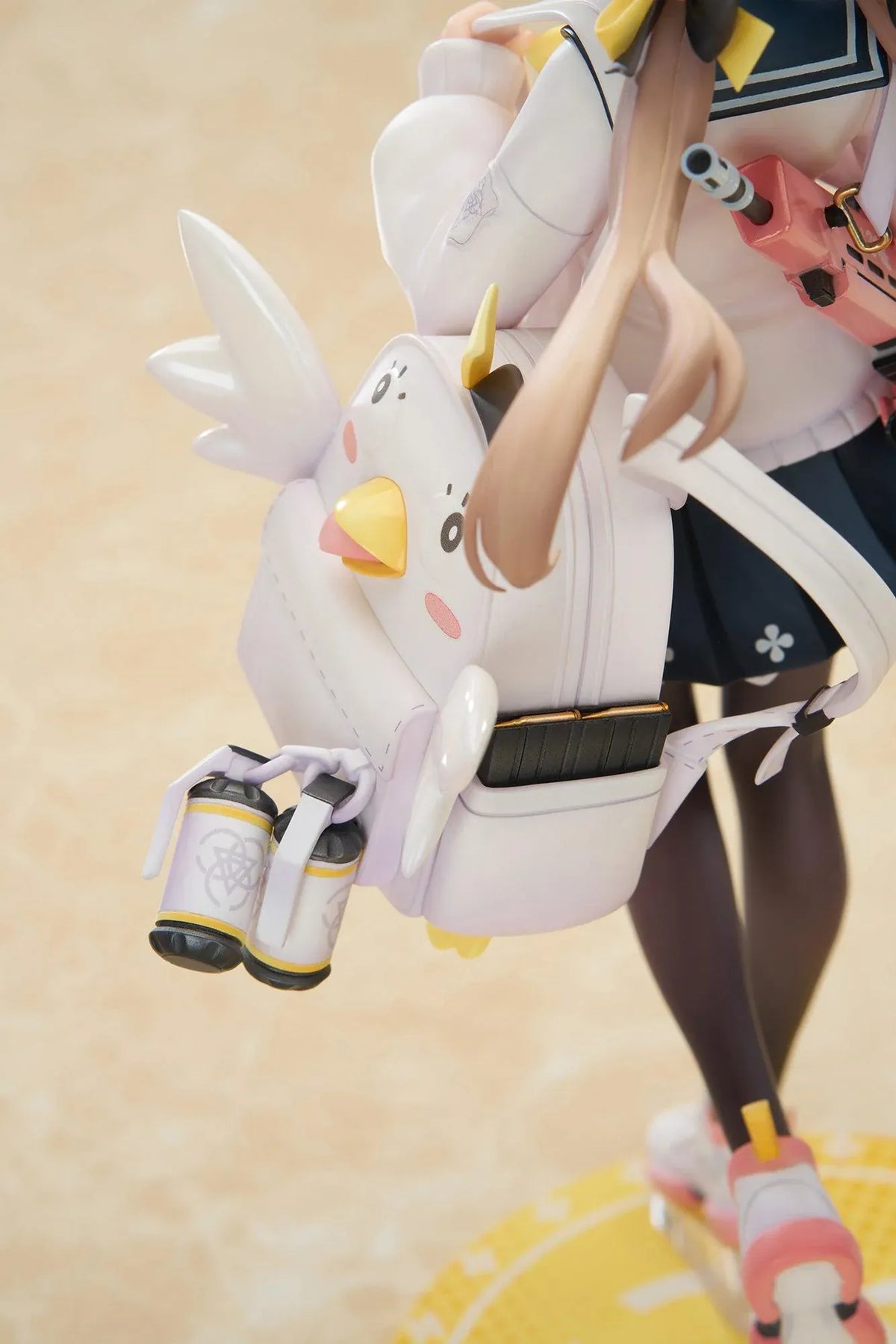 Blue Archive Hifumi figure smiling with one foot lifted, wearing a white cardigan and navy skirt, carrying a bird-themed bag and rifle on a yellow base.