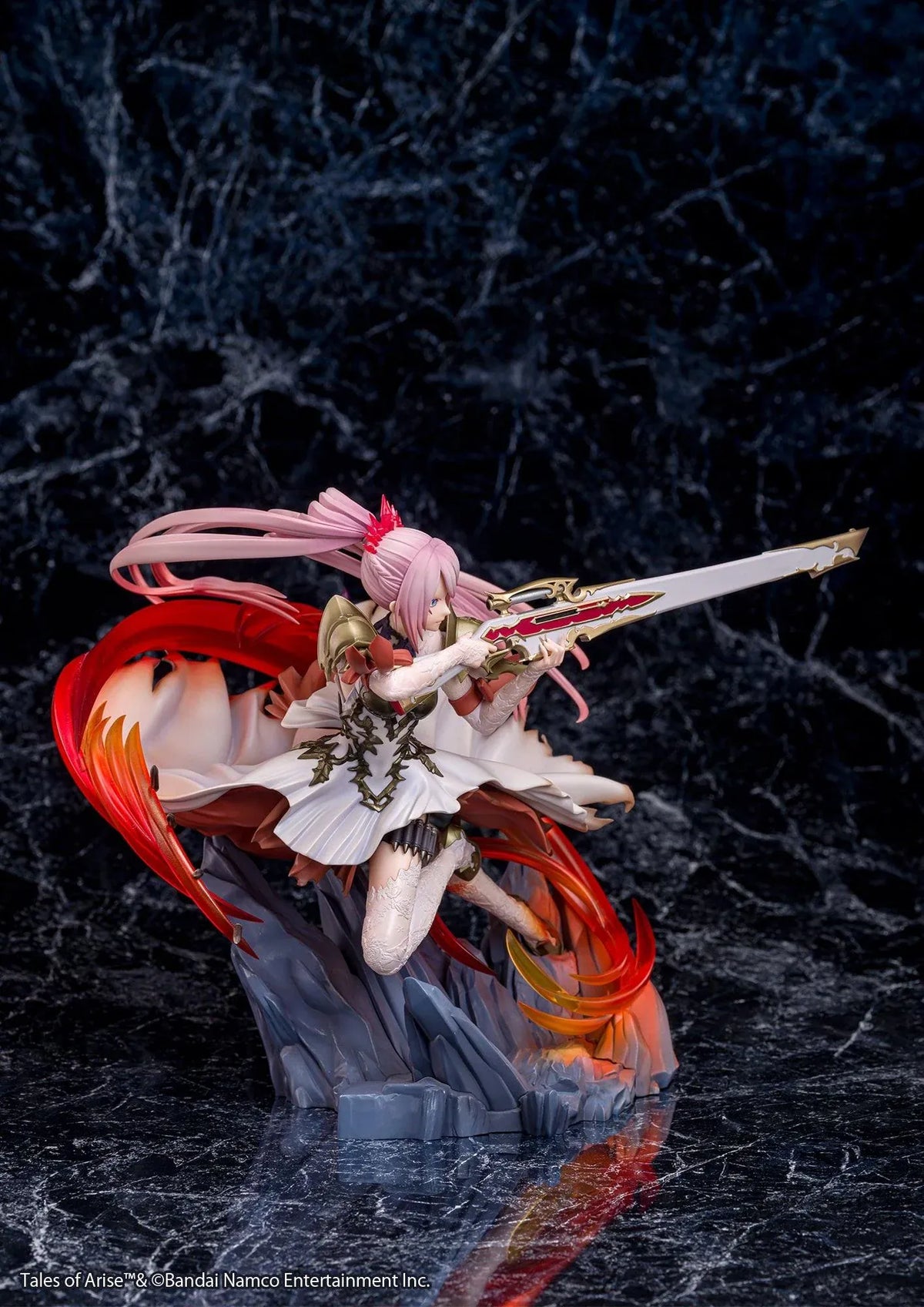 Tales of Arise Shionne 1/7 Scale Figure featuring a pink-haired anime character with blue eyes, an ornate white battle dress, gold armor, and lace stockings, aiming a detailed rifle while suspended in a dynamic pose surrounded by translucent red and orange effects on a rocky display base.