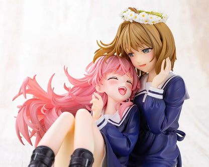 I Want to Love You Till Your Dying Day Sheena & Mimi 1/8 Scale Figure featuring pink-haired Sheena smiling with her eyes closed while leaning against blonde-haired Mimi. Both wear navy-blue school-inspired dresses and sit together on a textured grassy display base decorated with a white daisy flower crown.