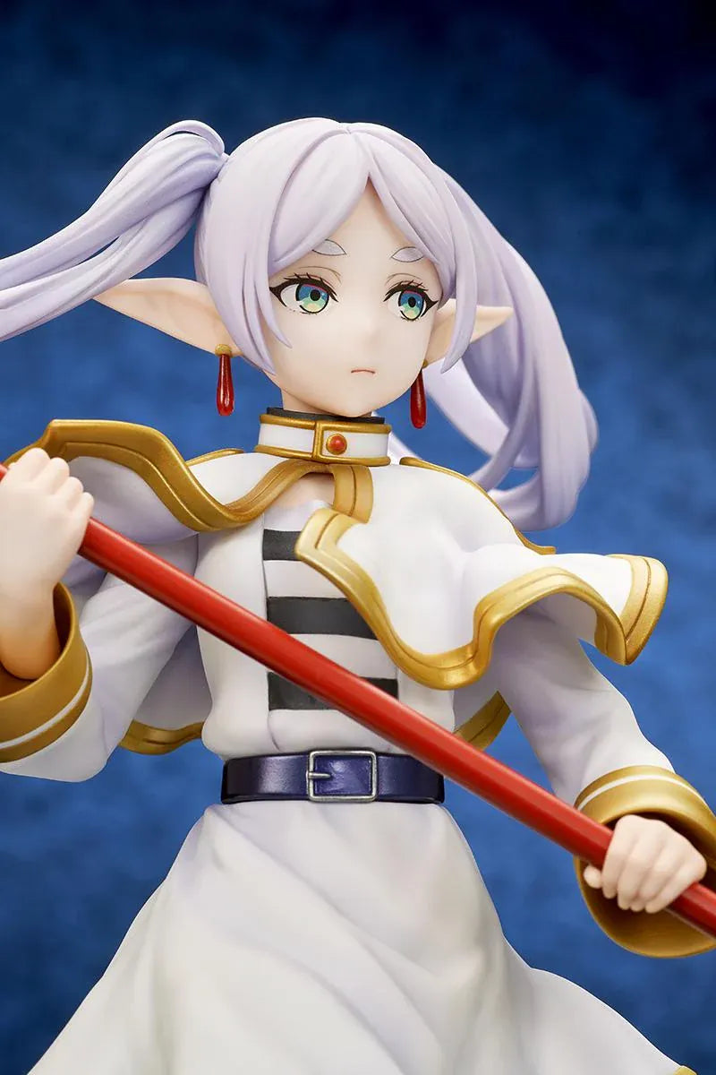 Frieren vs Aura 1/7 scale figure holding a red staff while wearing her white-and-gold mage outfit on a rounded display base.