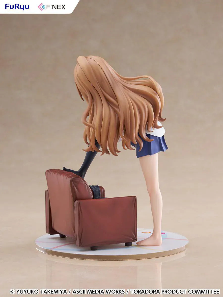 1/7 scale Toradora figure of Taiga Aisaka at home, barefoot and leaning on a leather armchair while pulling on a black thigh-high sock, wearing her school shirt and blue skirt.