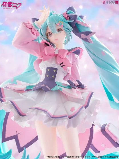 Hatsune Miku New School Term figure with turquoise twin-tails, a pink and white ruffled outfit, purple bows, and flower accents on a pink base.