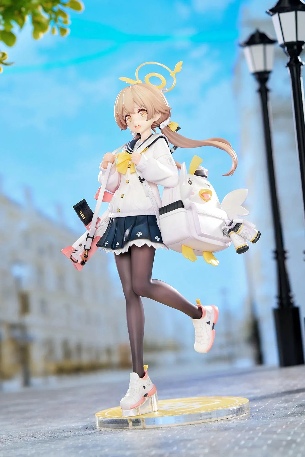 Blue Archive Hifumi figure smiling with one foot lifted, wearing a white cardigan and navy skirt, carrying a bird-themed bag and rifle on a yellow base.