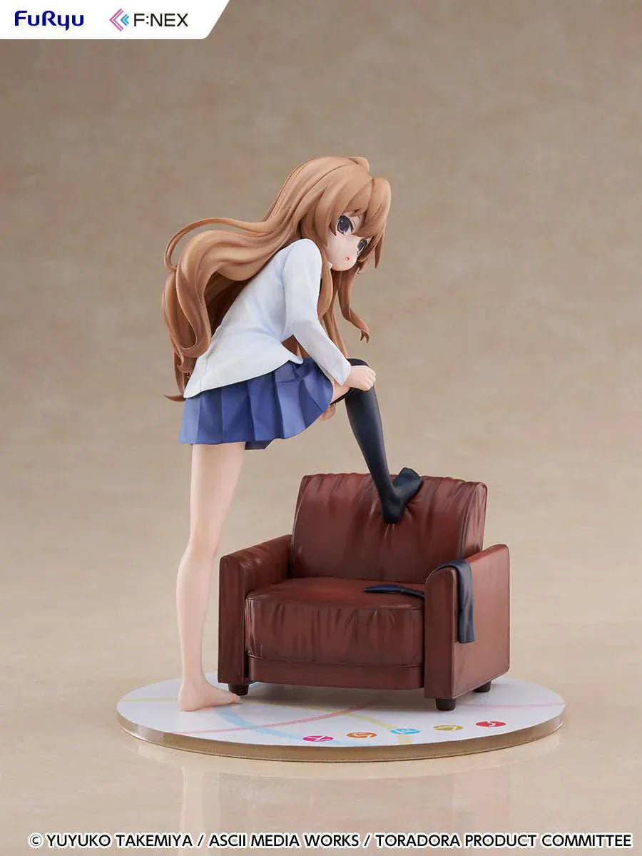 1/7 scale Toradora figure of Taiga Aisaka at home, barefoot and leaning on a leather armchair while pulling on a black thigh-high sock, wearing her school shirt and blue skirt.