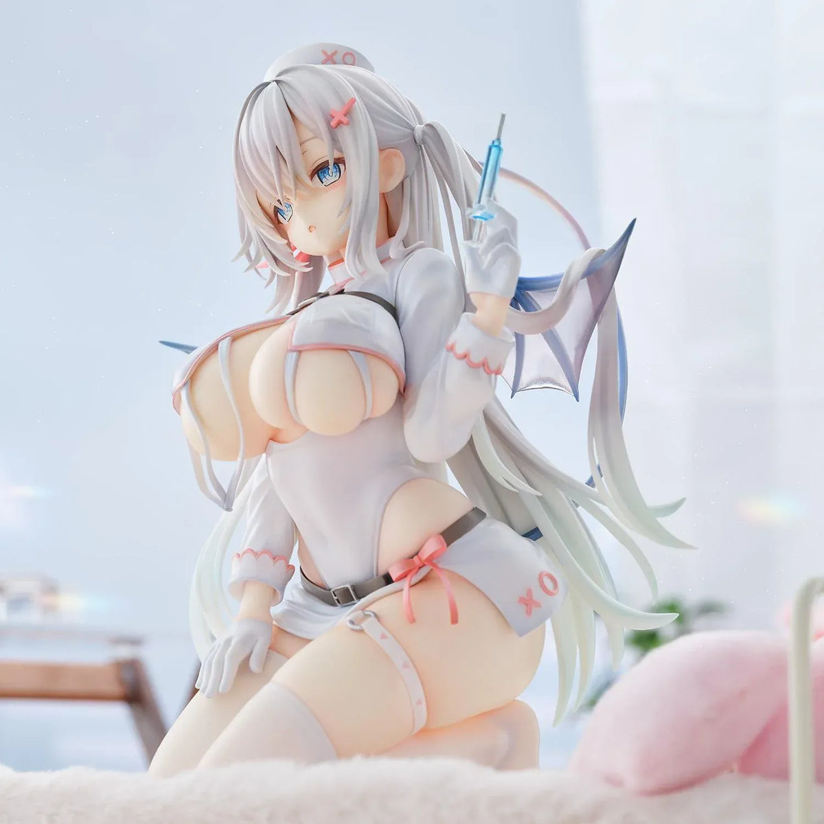 Succubus Nurse Makina figure kneeling in a white and pink nurse outfit with silver hair, batlike wings, a demon tail, and a translucent syringe.