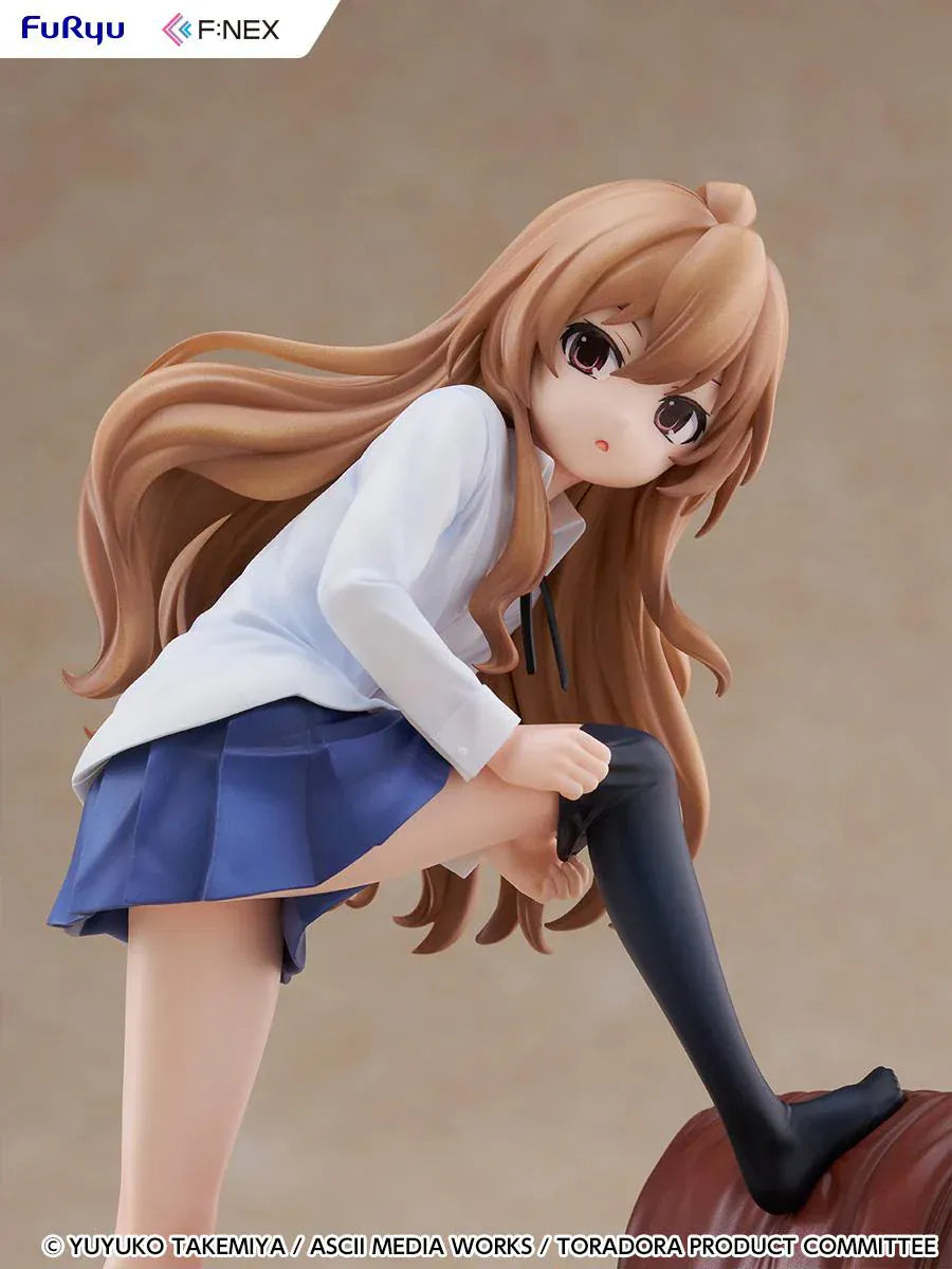 1/7 scale Toradora figure of Taiga Aisaka at home, barefoot and leaning on a leather armchair while pulling on a black thigh-high sock, wearing her school shirt and blue skirt.