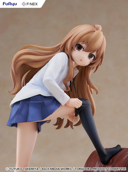 1/7 scale Toradora figure of Taiga Aisaka at home, barefoot and leaning on a leather armchair while pulling on a black thigh-high sock, wearing her school shirt and blue skirt.