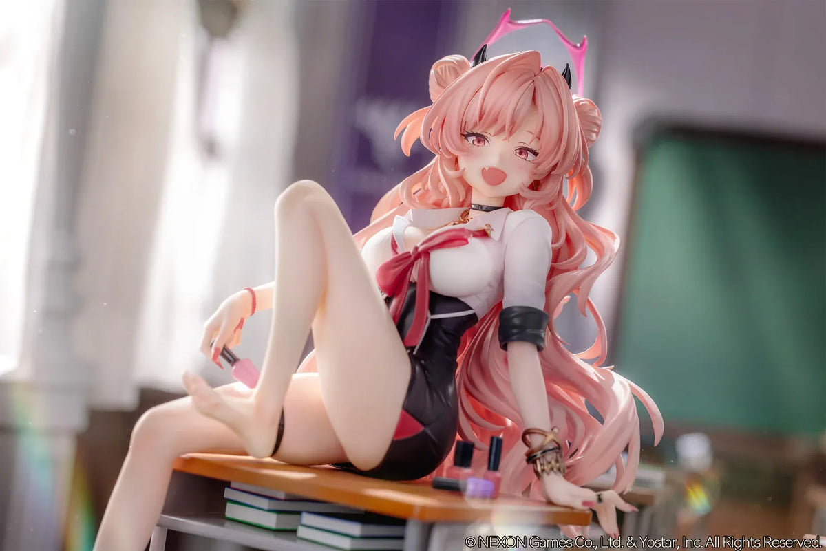 Blue Archive Kirara figure with long pink hair, black horns, and a pink halo, seated on a classroom desk beside nail polish bottles.