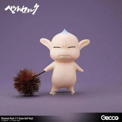 Berserk Chestnut Puck 1/1 Scale Soft Vinyl Figure by Gecco featuring a small cream-colored elf with oversized pointed ears, a tiny blue hair tuft, closed eyes, a grumpy expression, and a rounded body holding a large spiky brown chestnut burr.