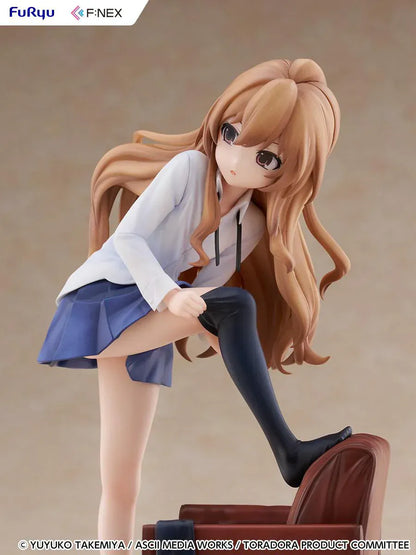 1/7 scale Toradora figure of Taiga Aisaka at home, barefoot and leaning on a leather armchair while pulling on a black thigh-high sock, wearing her school shirt and blue skirt.