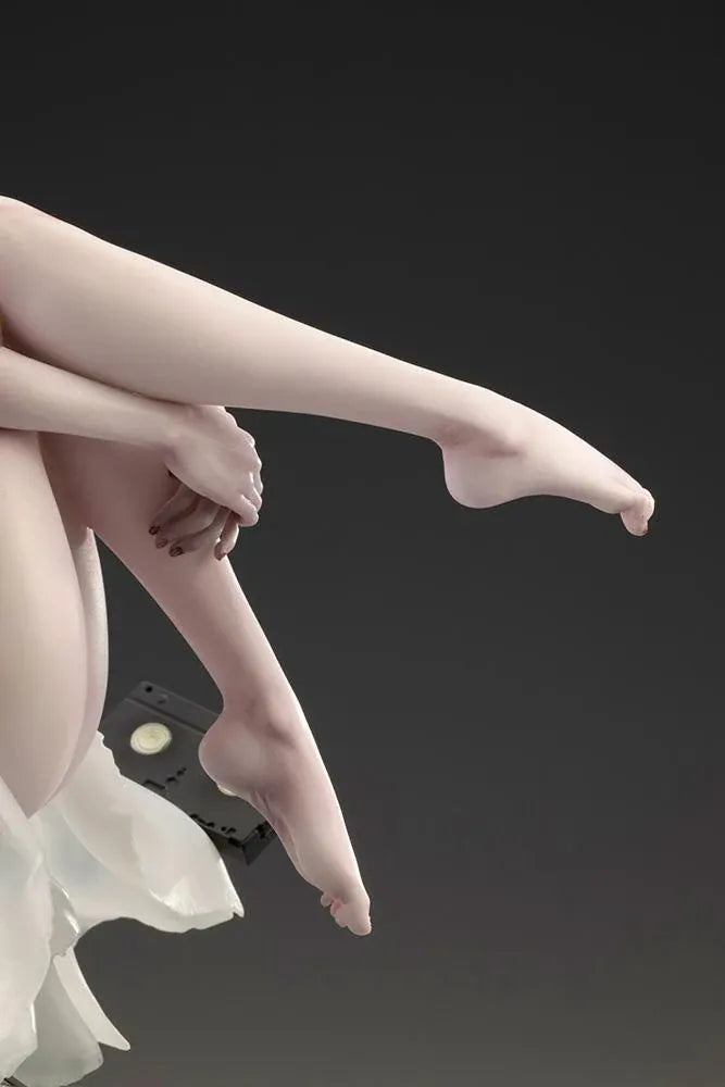 Sadako BISHOUJO Sadako 1/7 Scale Figure (Rerelease) featuring a long black-haired horror character wearing a flowing white dress, seated above a pile of VHS tapes with tangled black film ribbons.