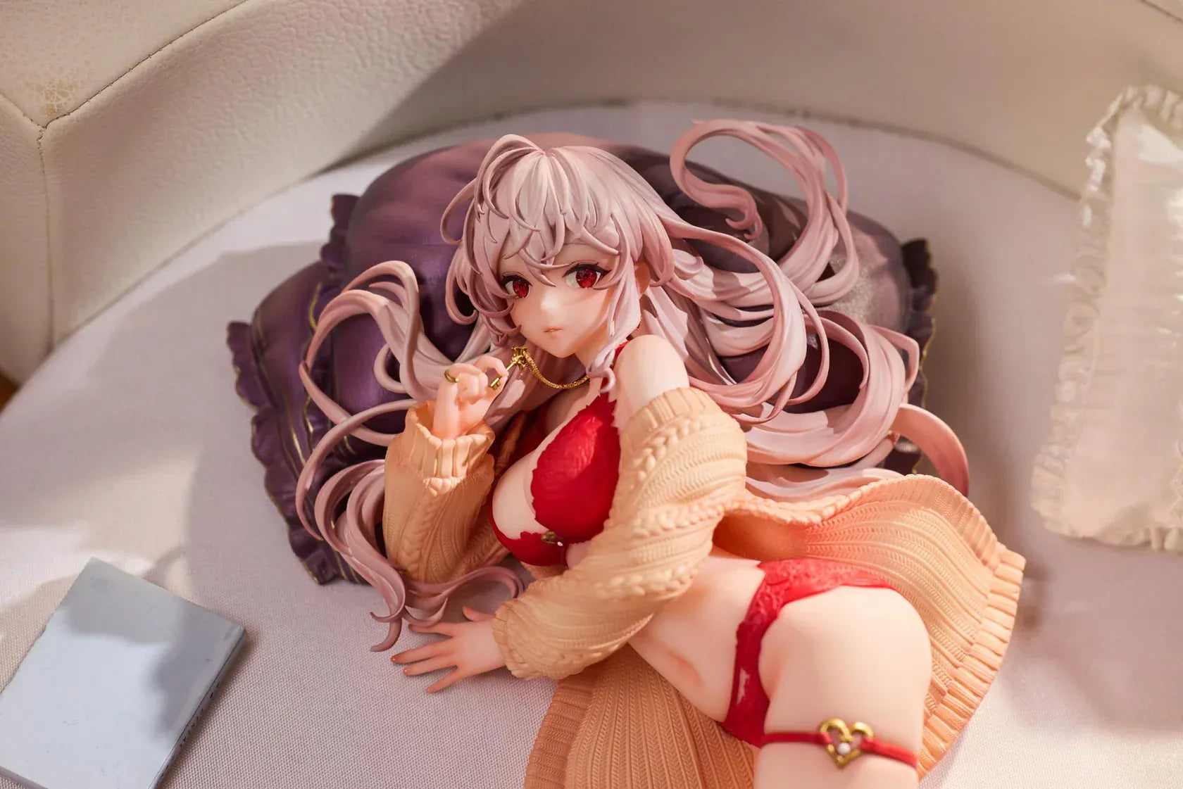 Makia 1/7 scale figure lying on a large fluffy white round base, wearing a cardigan and red lingerie, resting on a purple pillow