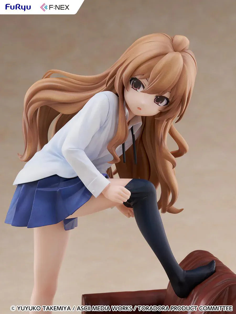 1/7 scale Toradora figure of Taiga Aisaka at home, barefoot and leaning on a leather armchair while pulling on a black thigh-high sock, wearing her school shirt and blue skirt.