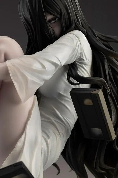 Sadako BISHOUJO Sadako 1/7 Scale Figure (Rerelease) featuring a long black-haired horror character wearing a flowing white dress, seated above a pile of VHS tapes with tangled black film ribbons.