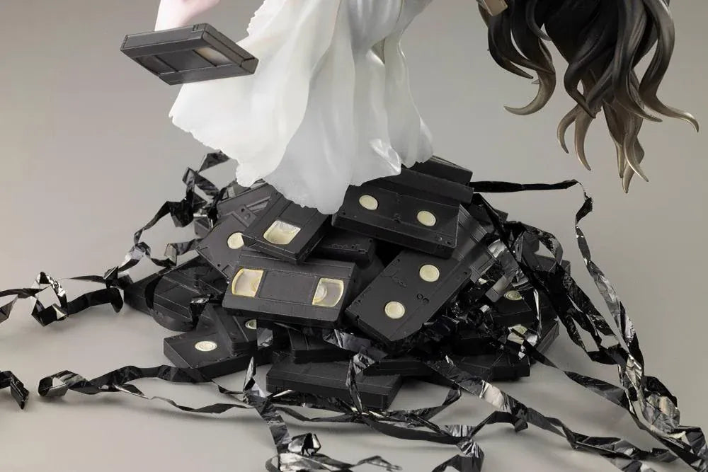 Sadako BISHOUJO Sadako 1/7 Scale Figure (Rerelease) featuring a long black-haired horror character wearing a flowing white dress, seated above a pile of VHS tapes with tangled black film ribbons.