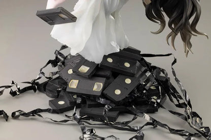Sadako BISHOUJO Sadako 1/7 Scale Figure (Rerelease) featuring a long black-haired horror character wearing a flowing white dress, seated above a pile of VHS tapes with tangled black film ribbons.