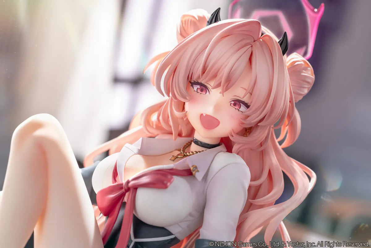 Blue Archive Kirara figure with long pink hair, black horns, and a pink halo, seated on a classroom desk beside nail polish bottles.