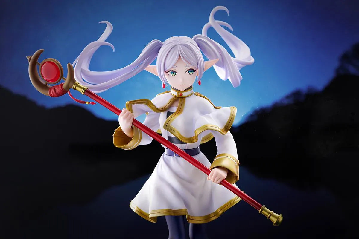 Frieren vs Aura 1/7 scale figure holding a red staff while wearing her white-and-gold mage outfit on a rounded display base.