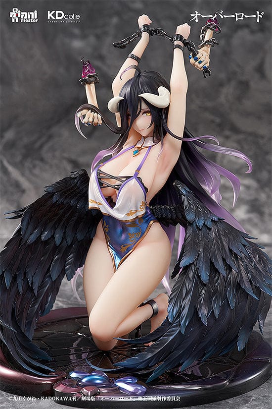 "Collectible figure of Albedo in a 'Restrained Version' pose with raised arms holding chains, adorned with black raven wings, wearing a blue and white costume with ornamental details, and sitting atop a circular base with decorative elements."