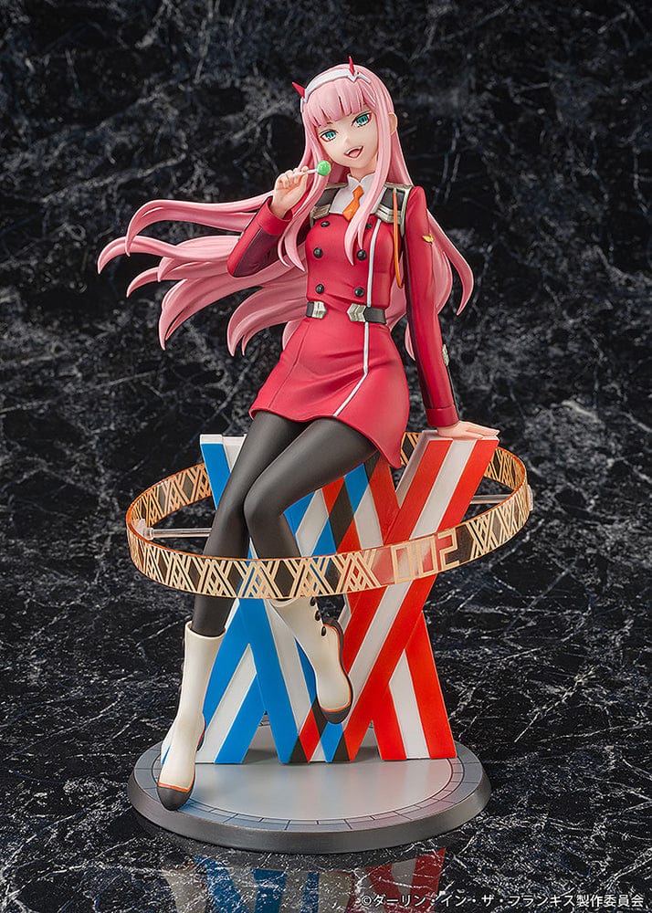 Darling in the Franxx Zero Two 1/7 Scale Figure in red outfit, sitting on a geometric base with "002" emblem, holding a lollipop with a mischievous expression.