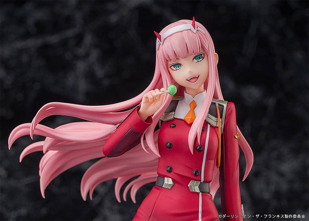 Darling in the Franxx Zero Two 1/7 Scale Figure in red outfit, sitting on a geometric base with "002" emblem, holding a lollipop with a mischievous expression.