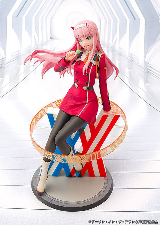 Darling in the Franxx Zero Two 1/7 Scale Figure in red outfit, sitting on a geometric base with "002" emblem, holding a lollipop with a mischievous expression.