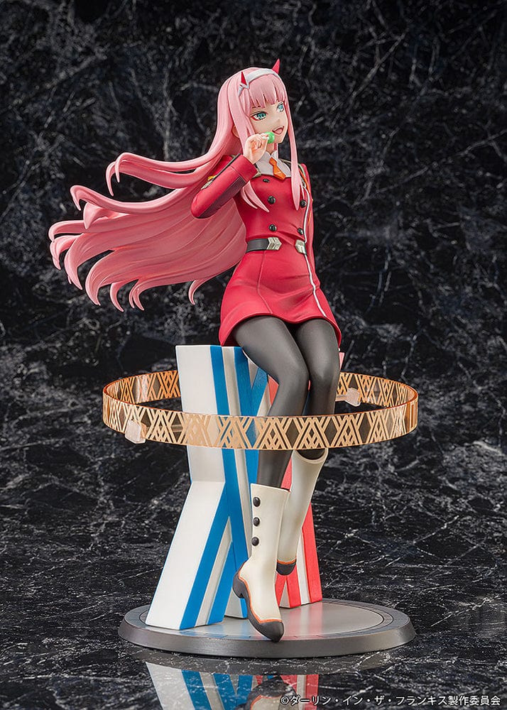 Darling in the Franxx Zero Two 1/7 Scale Figure in red outfit, sitting on a geometric base with "002" emblem, holding a lollipop with a mischievous expression.