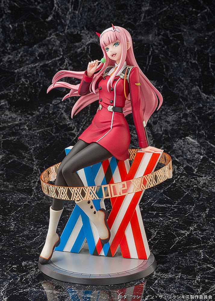 Darling in the Franxx Zero Two 1/7 Scale Figure in red outfit, sitting on a geometric base with "002" emblem, holding a lollipop with a mischievous expression.