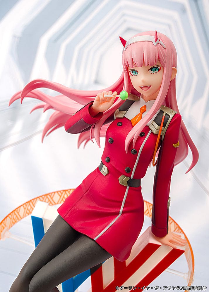 Darling in the Franxx Zero Two 1/7 Scale Figure in red outfit, sitting on a geometric base with "002" emblem, holding a lollipop with a mischievous expression.