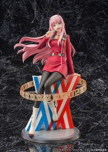 Darling in the Franxx Zero Two 1/7 Scale Figure in red outfit, sitting on a geometric base with "002" emblem, holding a lollipop with a mischievous expression.