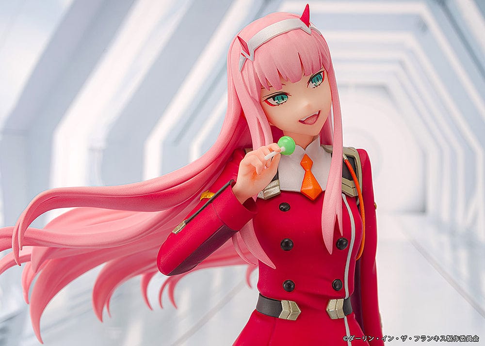 Darling in the Franxx Zero Two 1/7 Scale Figure in red outfit, sitting on a geometric base with "002" emblem, holding a lollipop with a mischievous expression.