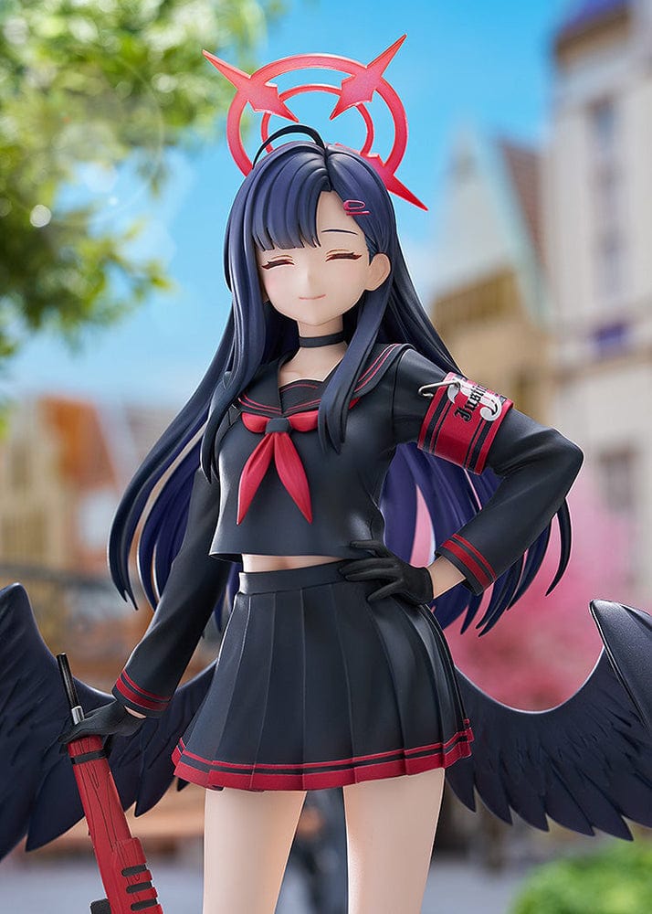 Blue Archive Ichika 1/7 scale figure in a dark school uniform with black wings, holding a red weapon and wearing a symbolic red halo-like accessory, with a calm, closed-eyed expression.