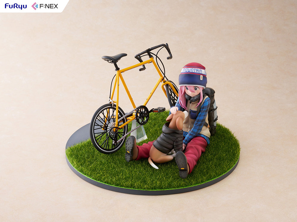 Nadeshiko Kagamihara (Season 3) 1/7 Scale Figure, depicting the character seated beside a yellow bicycle with detailed camping gear on a grassy base, capturing her joyful and carefree nature.