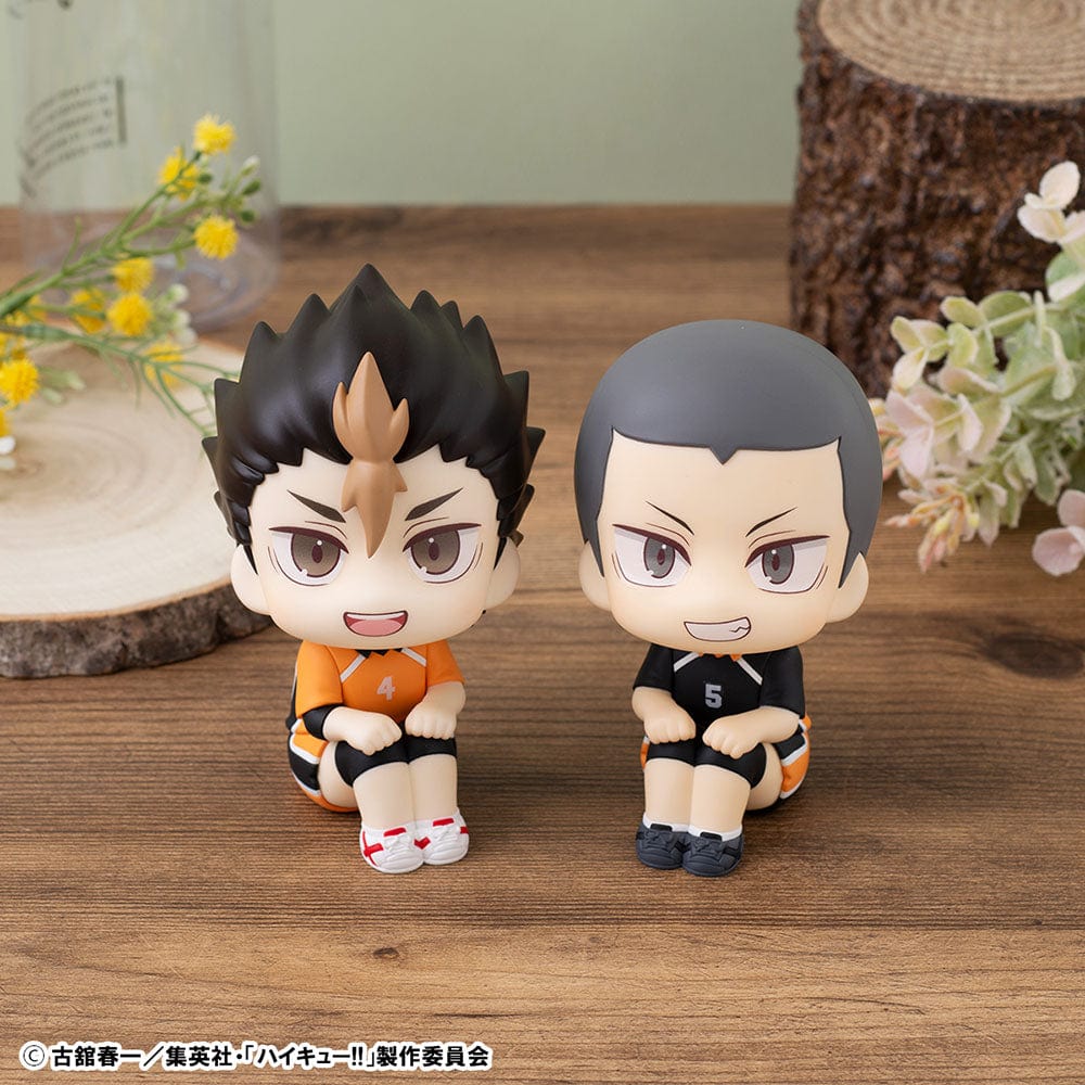 Haikyuu!! Look Up Series figures of Yu Nishinoya in orange and Ryunosuke Tanaka in black Karasuno High uniforms, sitting and looking up, held in human hands, with expressive features and volleyball-themed design.