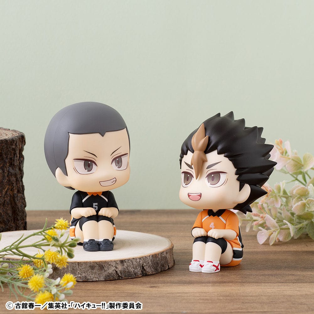 Haikyuu!! Look Up Series figures of Yu Nishinoya in orange and Ryunosuke Tanaka in black Karasuno High uniforms, sitting and looking up, held in human hands, with expressive features and volleyball-themed design.