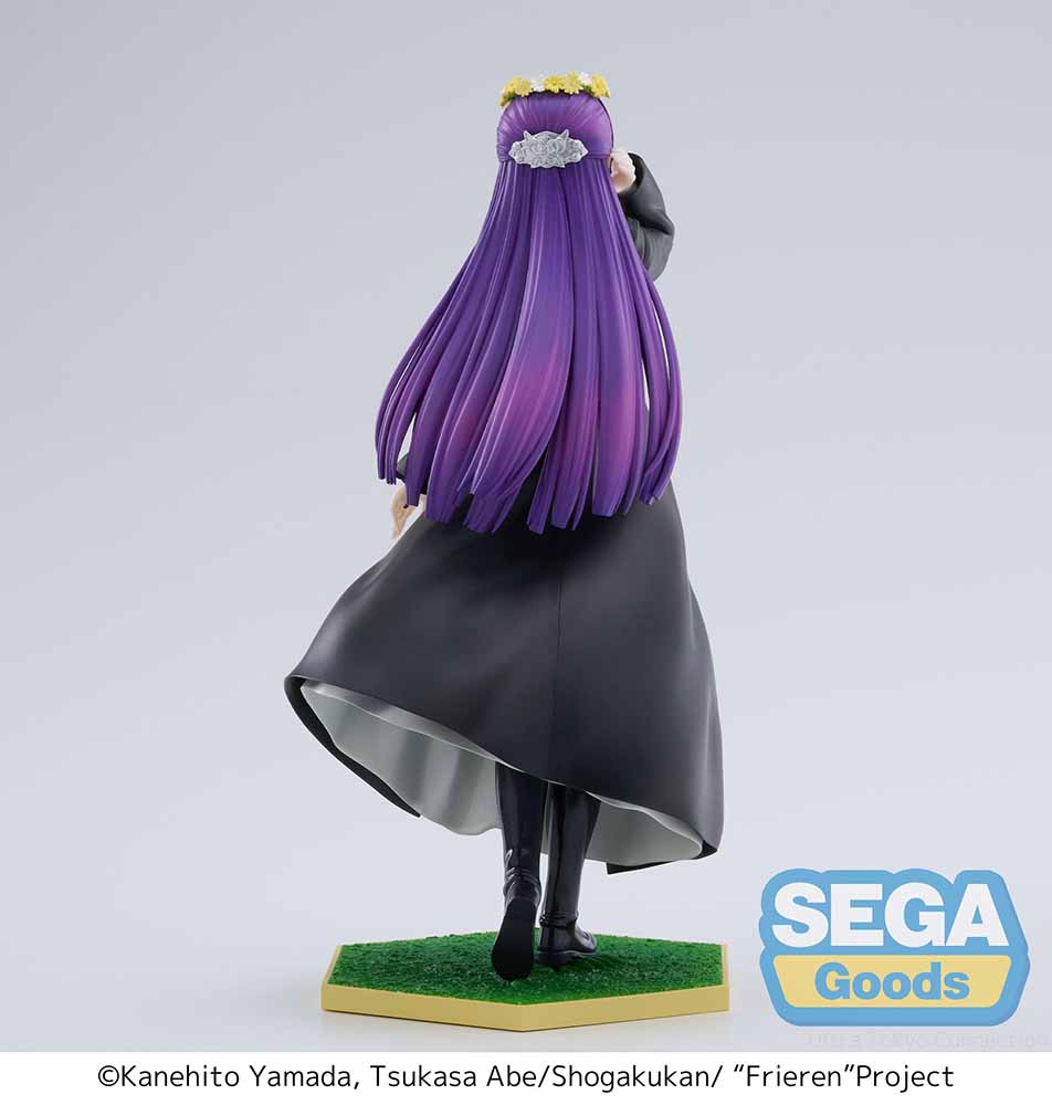 Frieren: Beyond Journey's End Luminasta Fern (Flower Garden) Figure featuring Fern in a long black coat, gray dress, and daisy crown on a grass-textured hexagonal base, set against a white background.