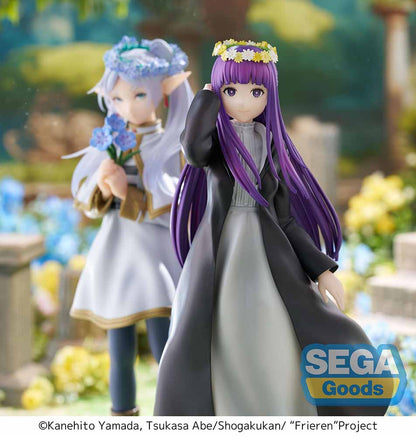 Frieren: Beyond Journey's End Luminasta Fern (Flower Garden) Figure featuring Fern in a long black coat, gray dress, and daisy crown on a grass-textured hexagonal base, set against a white background.