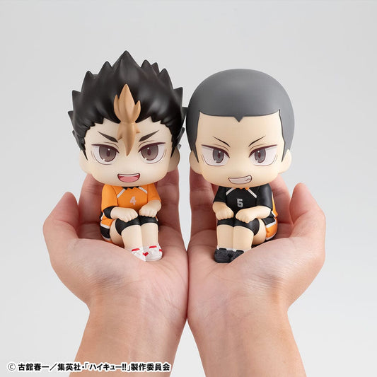 Haikyuu!! Look Up Series figures of Yu Nishinoya in orange and Ryunosuke Tanaka in black Karasuno High uniforms, sitting and looking up, held in human hands, with expressive features and volleyball-themed design.